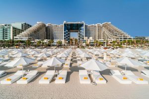 Toit de vacances en bord de mer avec parasols blancs et hôtels modernes en arrière-plan à Dubai.