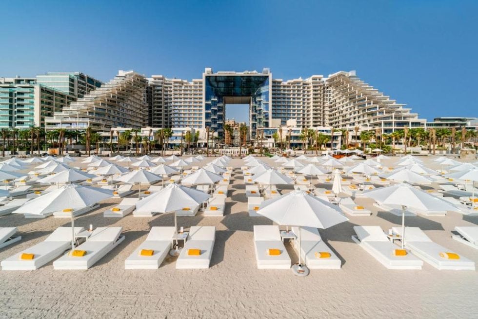 Toit de vacances en bord de mer avec parasols blancs et hôtels modernes en arrière-plan à Dubai.