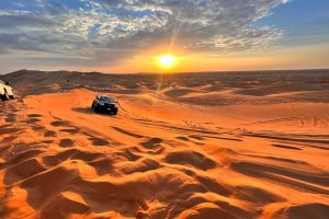 Voitures 4x4 traversant les dunes du désert au lever du soleil.