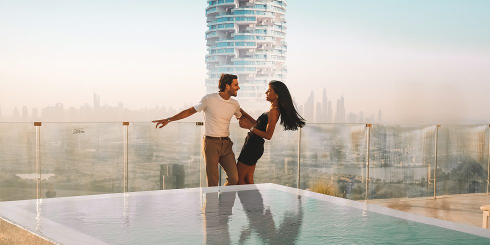 Vue d'une terrasse avec piscine surplombant la ville de Dubaï, avec un gratte-ciel moderne en arrière-plan, ambiance urbaine et romantique.