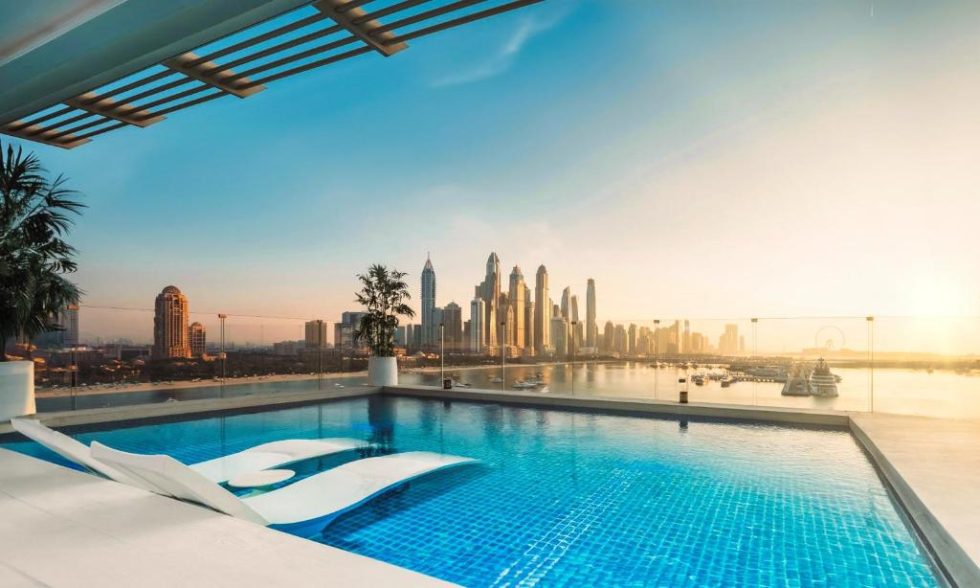 Luxueux rooftop avec piscine infinity offrant une vue imprenable sur la skyline de Dubaï au coucher du soleil. Parfait pour des vacances de rêve et la détente.
